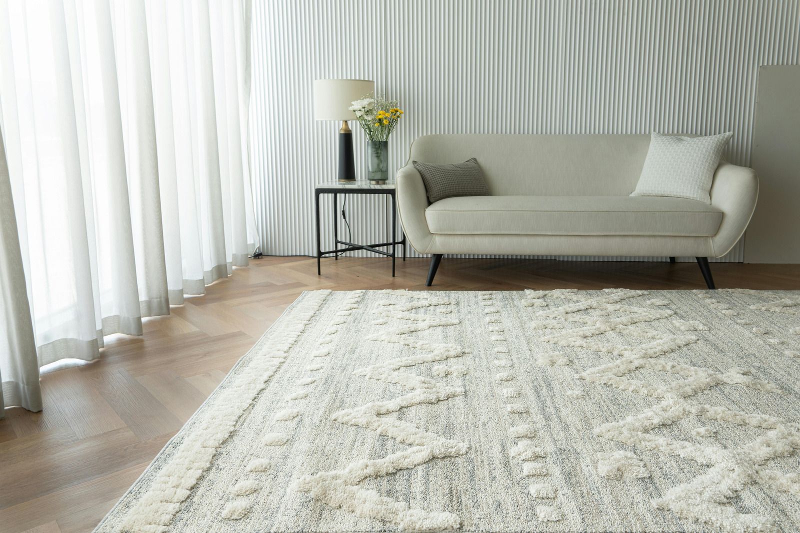 Bright living room with white sofa, patterned rug, and curtains by a window