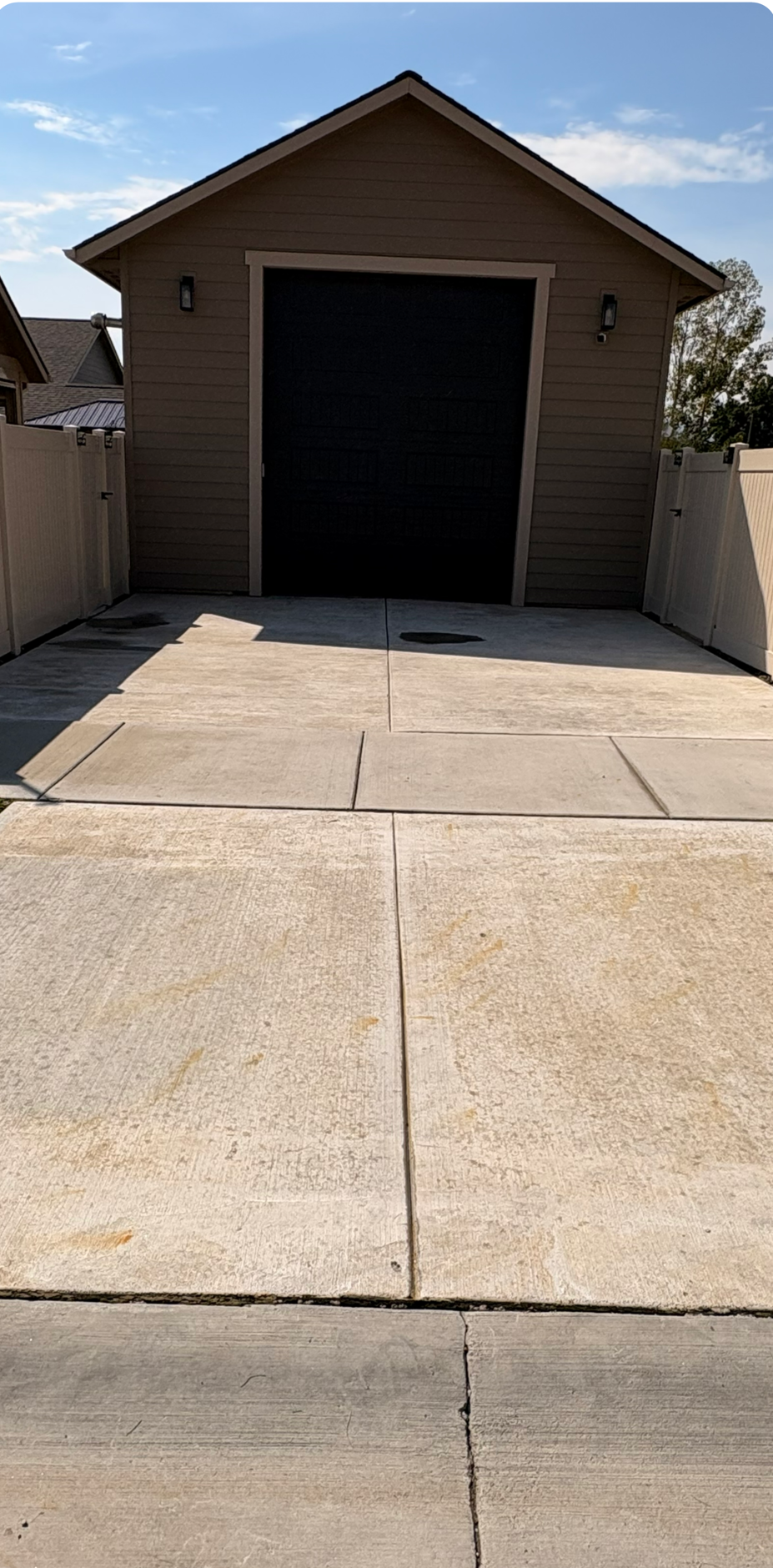 Detached brown garage with open door, concrete driveway, and bright sunlight.