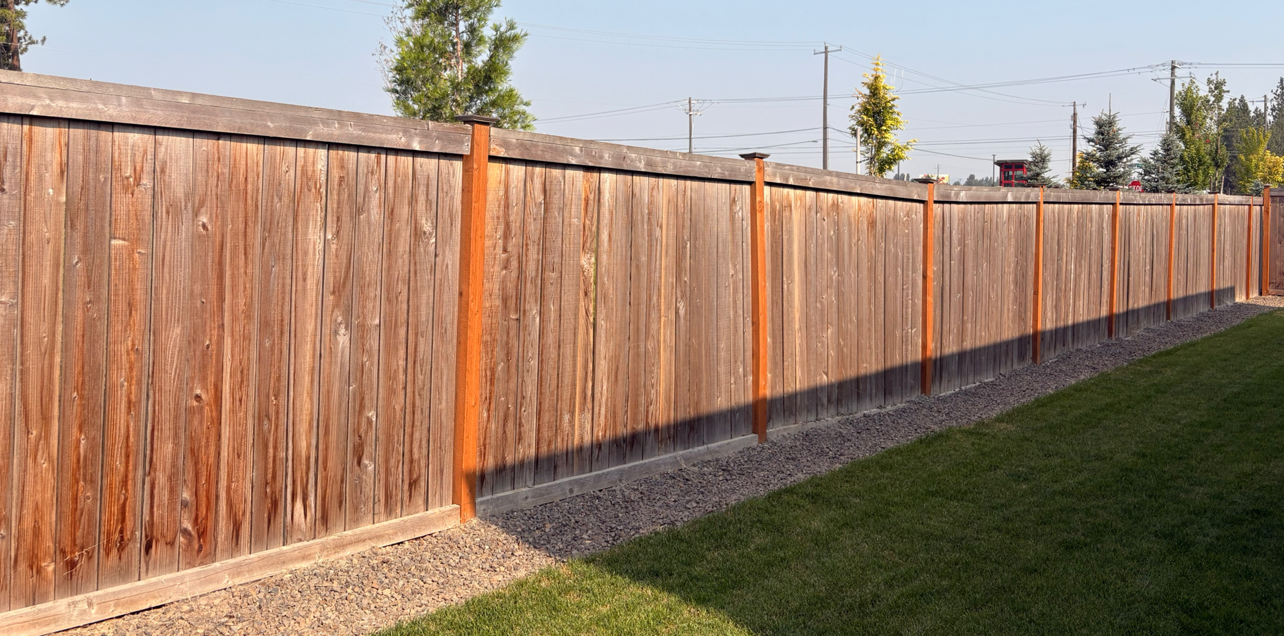 Long wooden privacy fence along a grassy yard on a sunny day