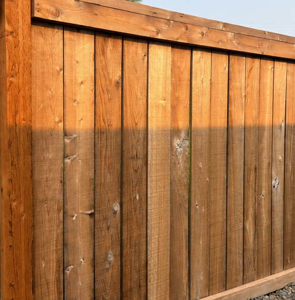 Sunlit wooden fence with vertical planks and a diagonal top rail