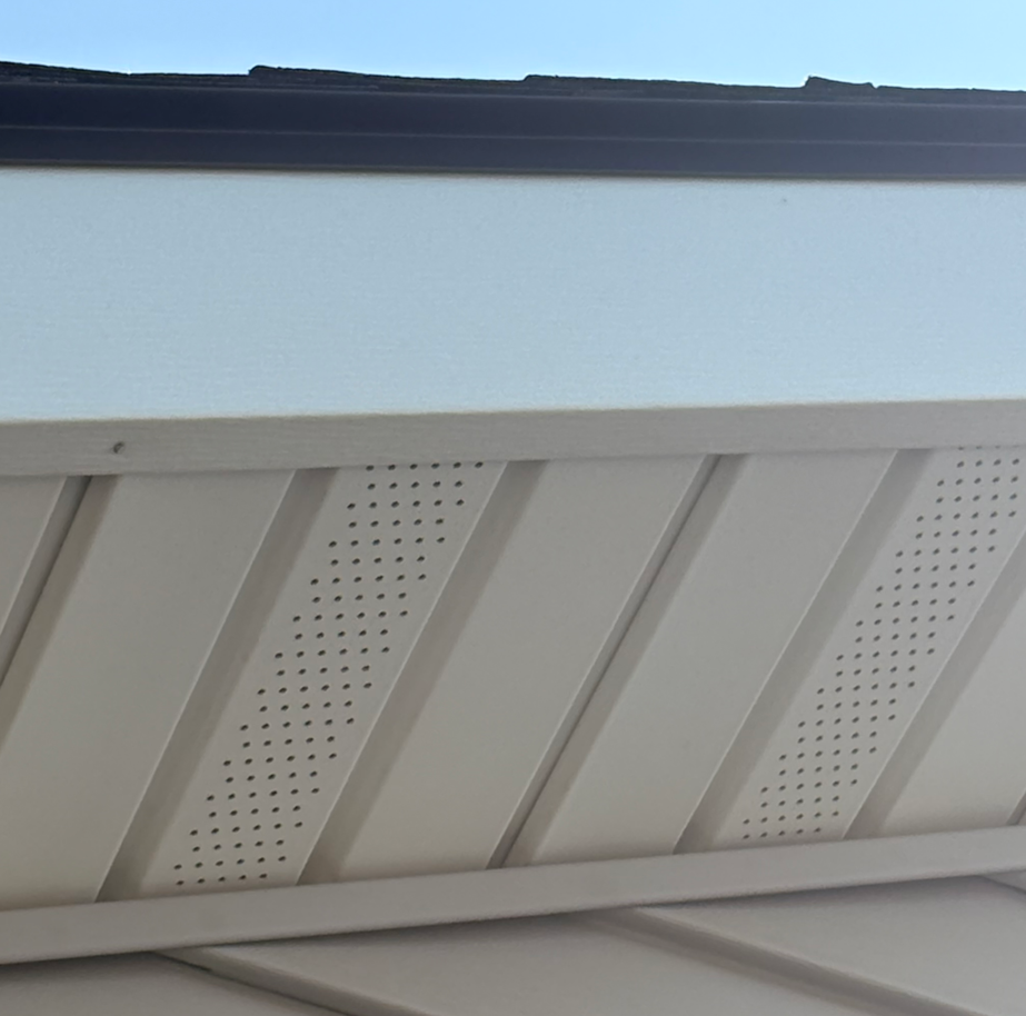 Close-up of a white building soffit with vent panels and a blue sky above