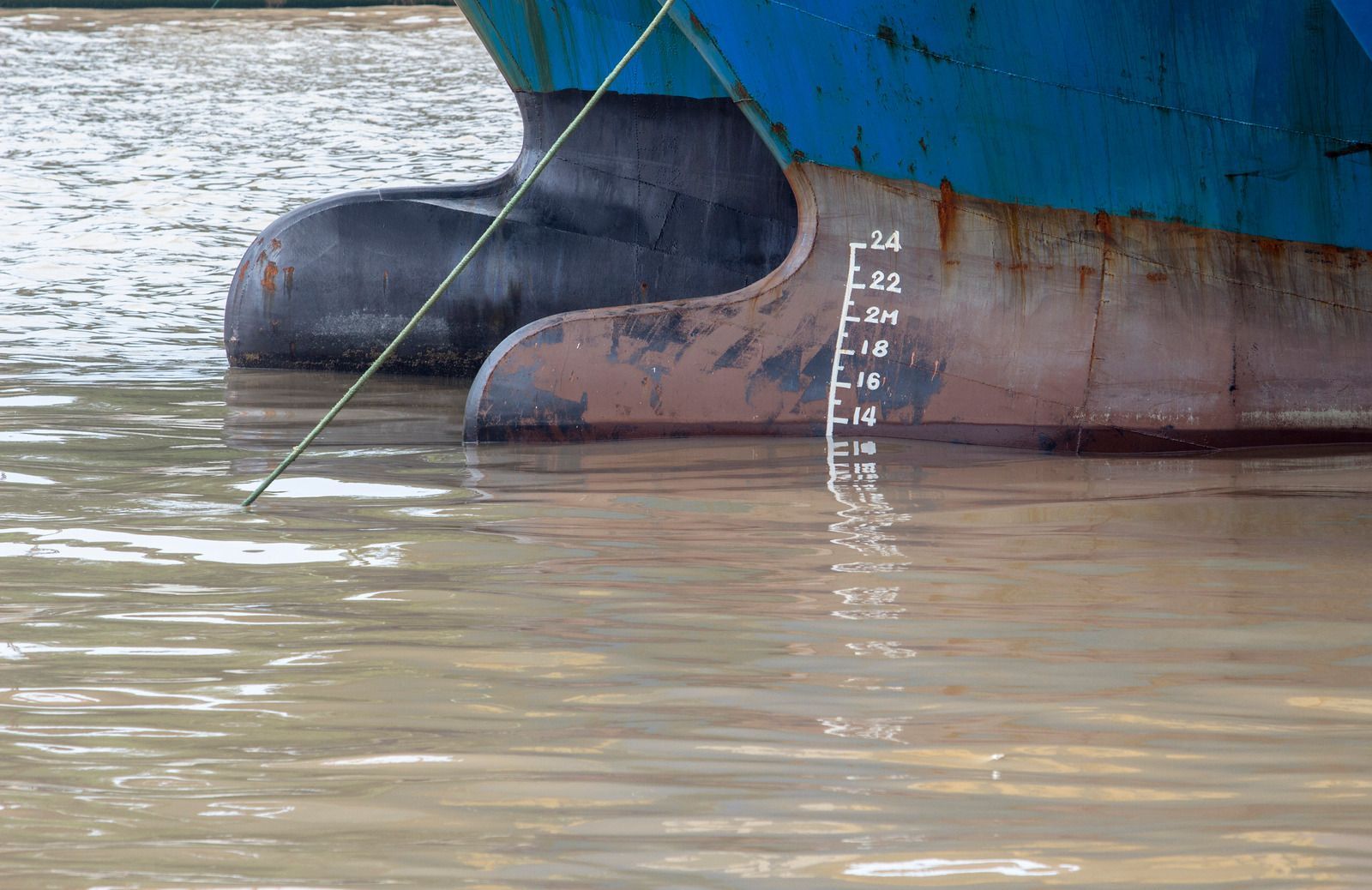 Close-up of a ship hull in muddy water, with a depth scale marked on the side.