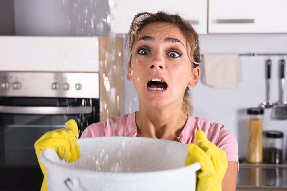 Worried Woman Holding A Bucket — Plumbers in Harlaxton, QLD