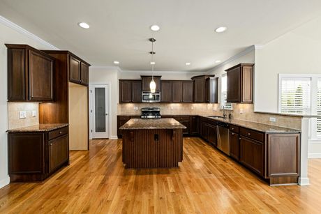 Modern kitchen with dark wood cabinets, granite countertops, hardwood floors, and a central island.