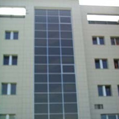 Edificio beige con un grande pannello di vetro e file di finestre.