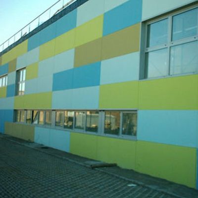 Esterno dell'edificio con pannelli rettangolari colorati in blu, giallo e marrone chiaro, con finestre.
