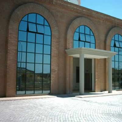 Edificio in mattoni con finestre ad arco riflettenti; ingresso con colonne.