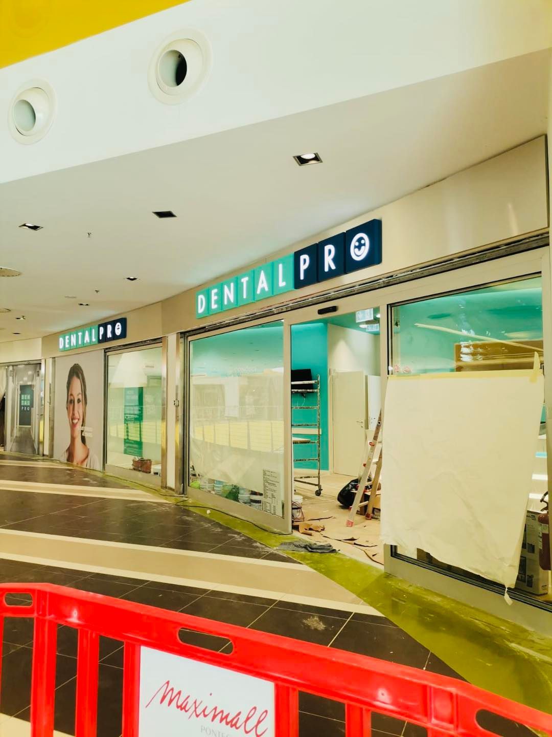 Vetrina del negozio Dental Pro in un centro commerciale con barriera rossa e lavori in corso.