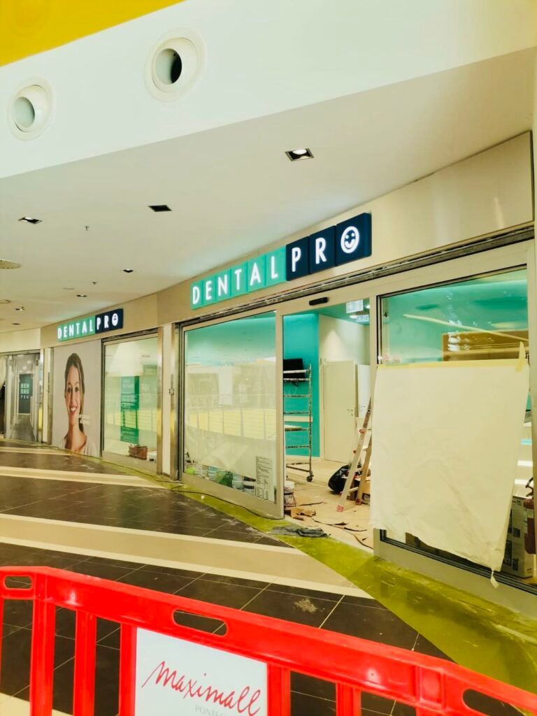 Vetrina di Dental Pro in costruzione in un centro commerciale, con una barriera rossa davanti.