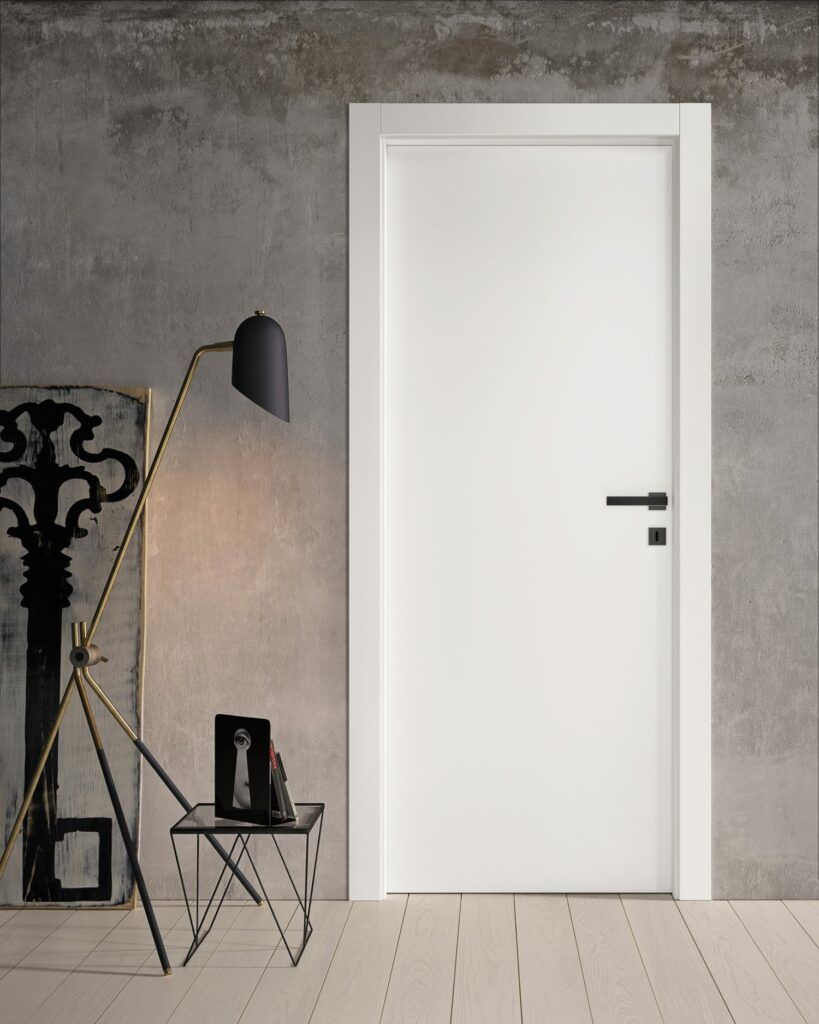 Porta interna bianca con maniglia e finiture nere, accanto a un'opera d'arte astratta e una lampada.