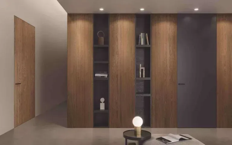 Interni moderni con pannelli in legno alle pareti, scaffalature integrate, porta grigio scuro, illuminazione da incasso e un tavolino con lampada.