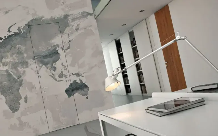 Interno di un ufficio moderno con parete raffigurante una mappa del mondo, scrivania, lampada e telefono.