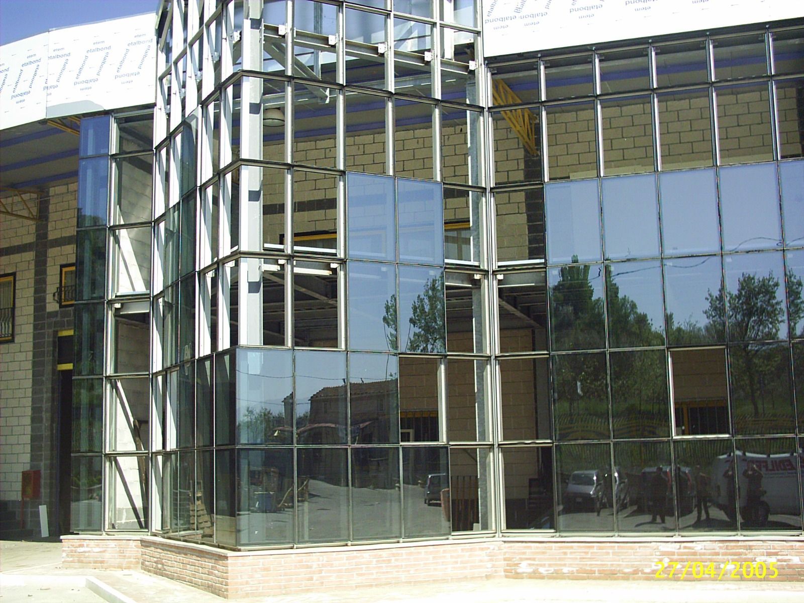 Facciata di un edificio moderno con finestre in vetro riflettente e struttura in metallo.