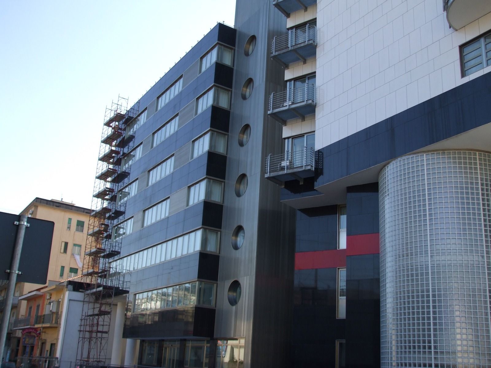 Edificio moderno con pannelli neri e argento, impalcature sulla sinistra.