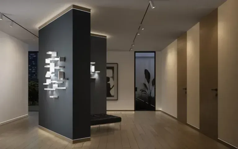 Interno di una galleria d'arte moderna con pareti dai colori neutri, luci espositive e una panca.