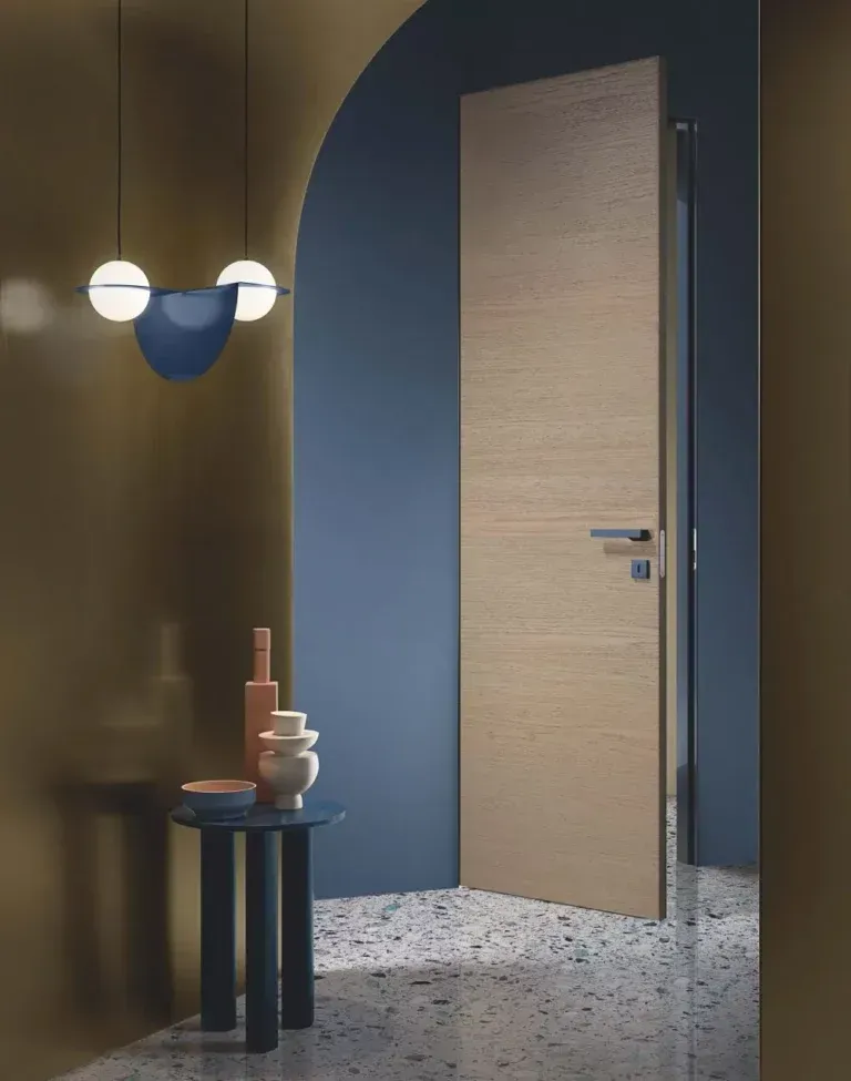 Interno moderno con una porta in legno, pareti blu e oro, un tavolino e una lampada a sospensione.