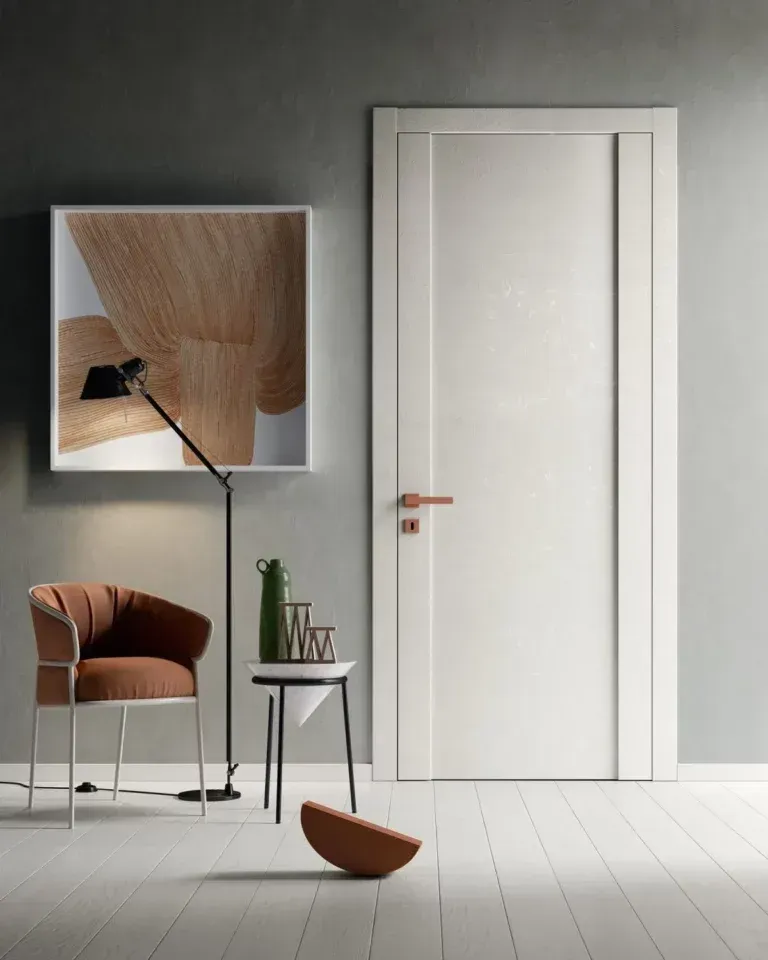 Porta bianca in una stanza moderna con opere d'arte, lampada, sedia e tavolino.