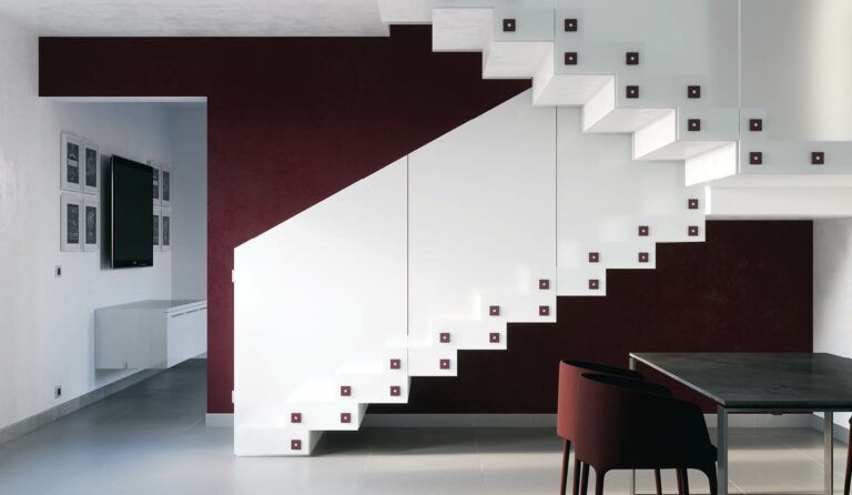 Moderna scala sospesa bianca con parete decorativa color bordeaux, tavolo da pranzo nero e sedia.