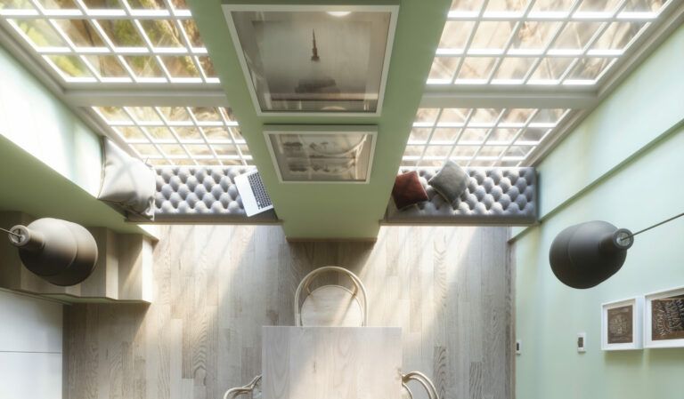 Sala da pranzo con soffitto in vetro, pavimento in legno chiaro, luci sospese e quadri incorniciati.