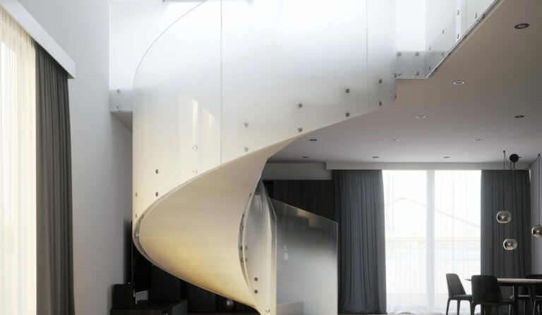Una moderna scala a chiocciola bianca con pannelli in vetro sale in un interno luminoso e aperto.
