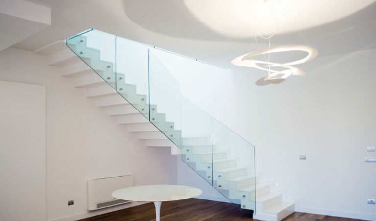 Scala bianca con ringhiera in vetro. Interni luminosi e moderni.