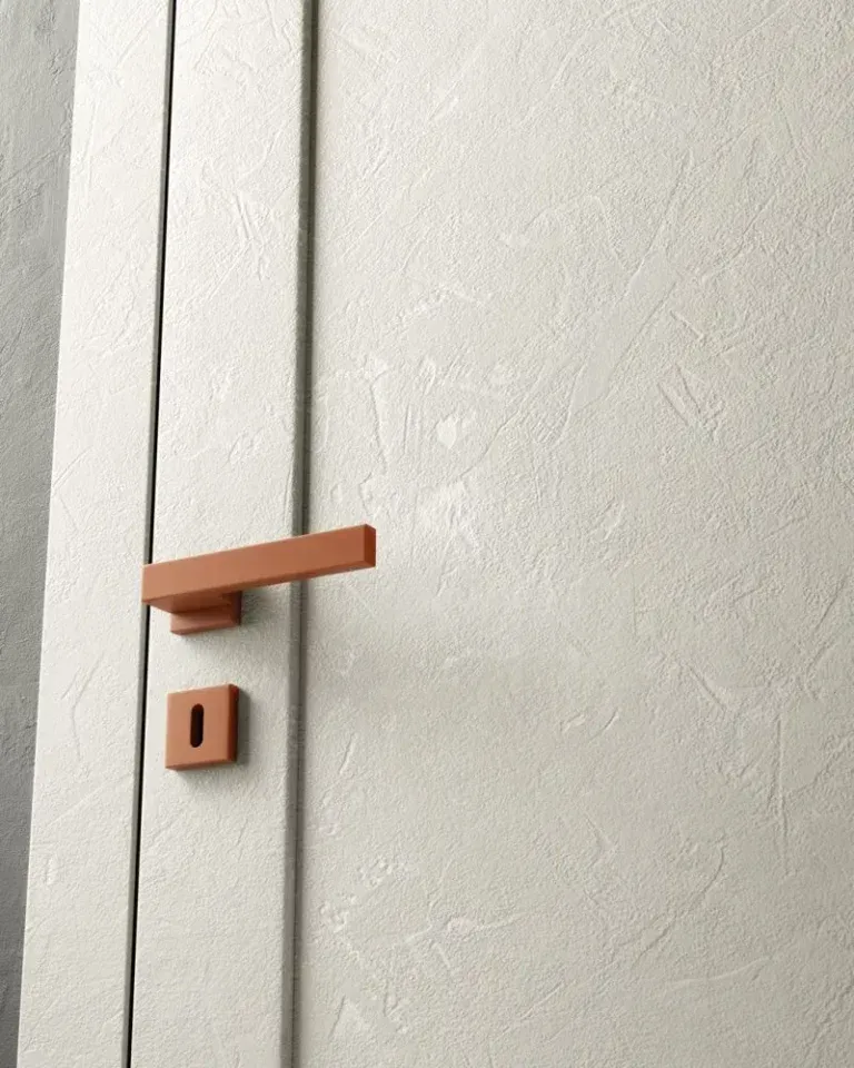 Porta bianca con maniglia e serratura color terracotta.