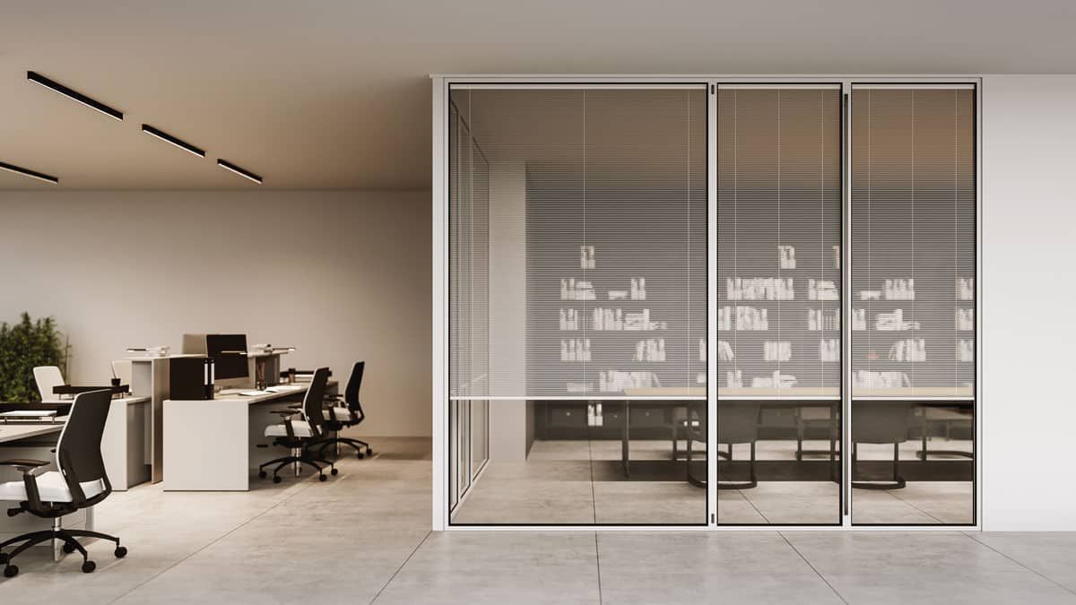 Interno di un ufficio con porte in vetro, persiane e scrivanie.