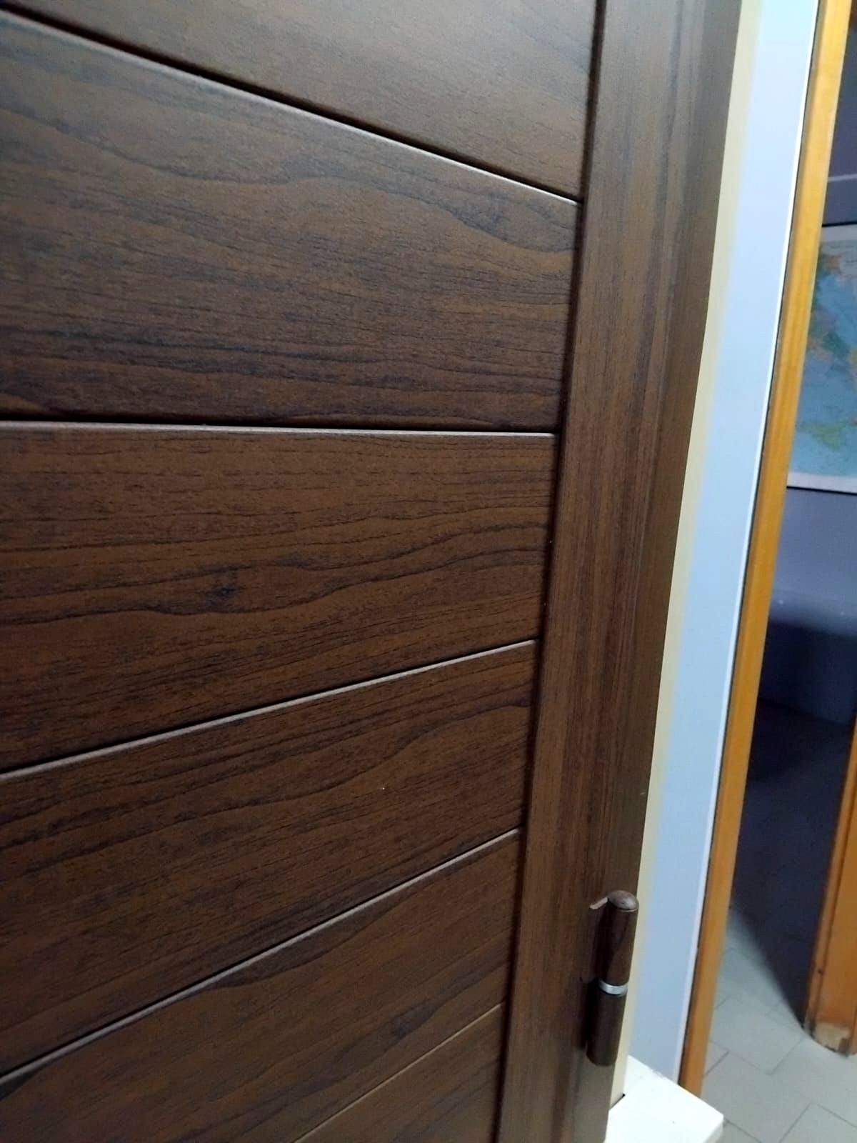 Primo piano di una porta marrone con pannelli orizzontali, telaio abbinato e cerniera a vista.