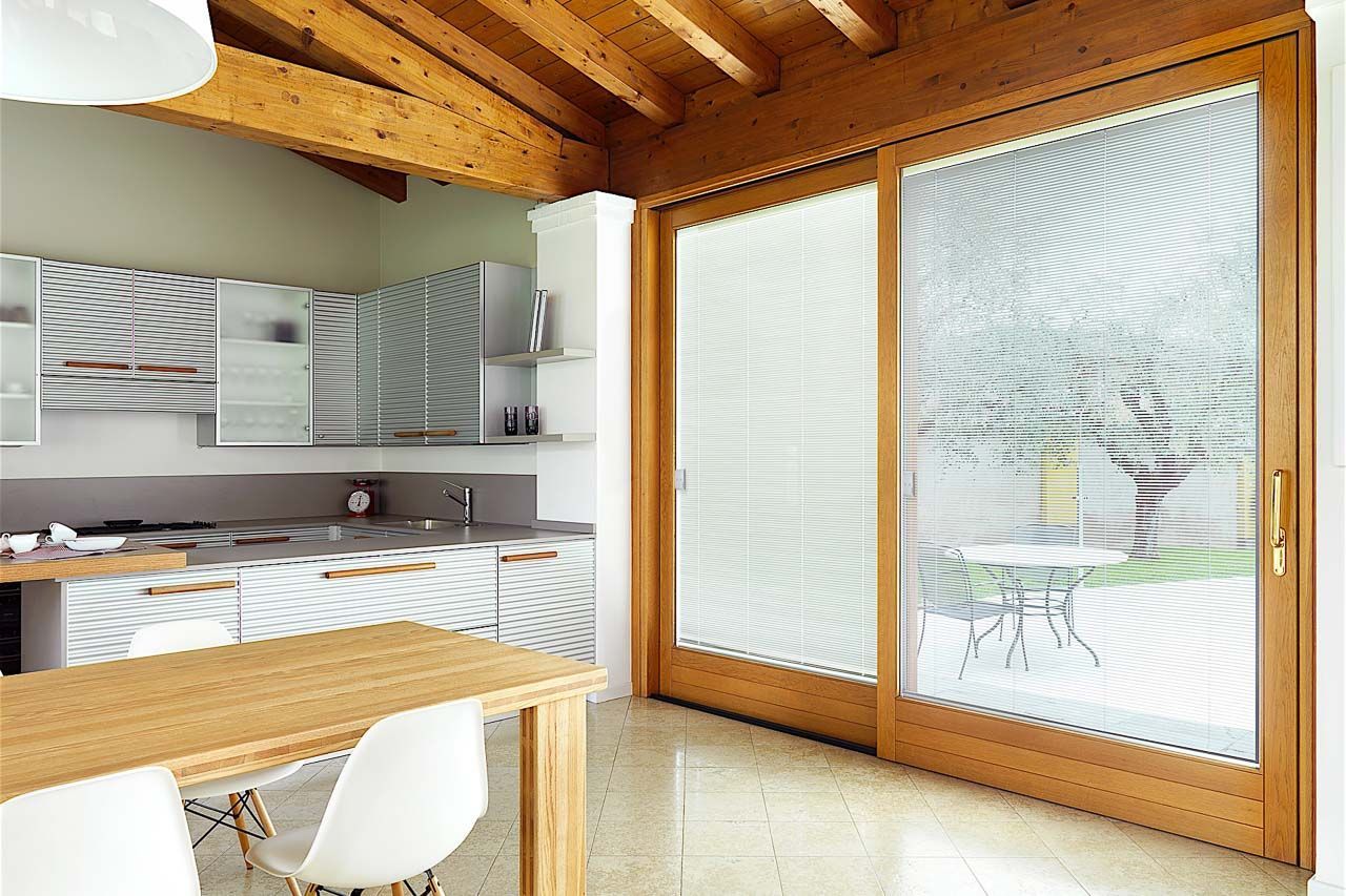 Interno della cucina con porta scorrevole in legno, tavolo e mobili.