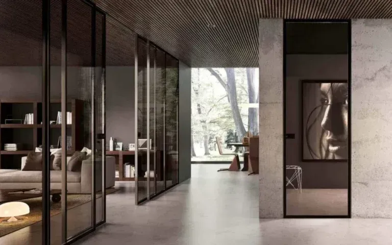 Moderno corridoio interno con pareti in vetro, pavimenti in cemento e un'opera d'arte incorniciata.