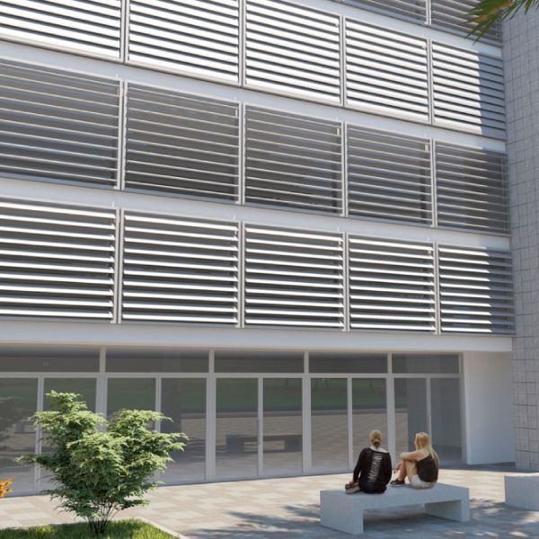 Edificio moderno con persiane orizzontali argentate, vetrina in vetro, due persone sedute su una panchina di cemento.