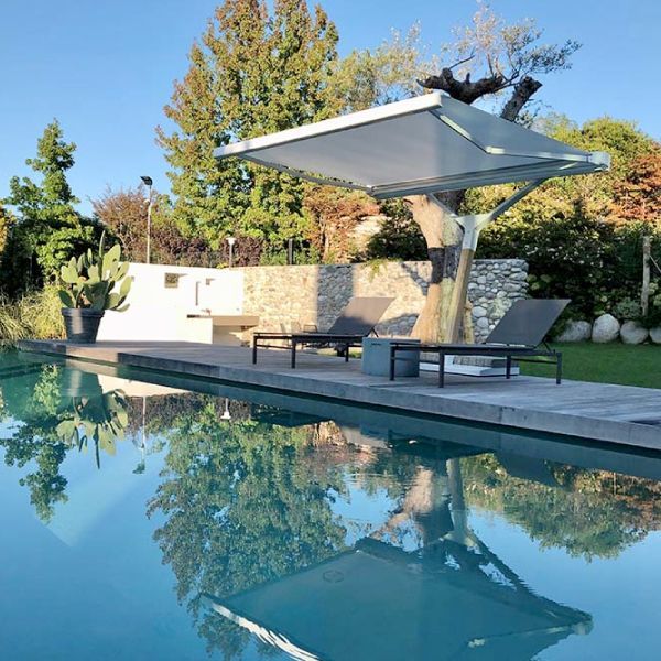 Scena a bordo piscina con un moderno baldacchino sopra due chaise longue che si riflettono nell'acqua.