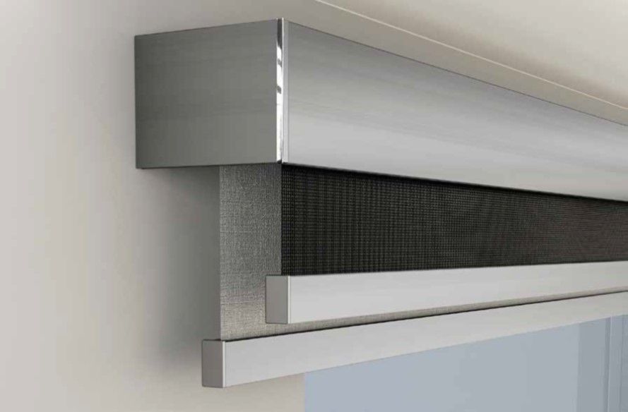 Primo piano di moderne tende a rullo doppie. La parte superiore è in metallo massiccio, la parte inferiore è in rete scura traslucida e la cornice è bianca.