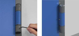 La mano di una persona che usa uno strumento per regolare la cerniera di una porta blu.