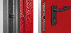 Primo piano di una porta rossa con maniglia nera e meccanismo di serratura. Un'altra porta è visibile in grigio.