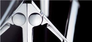 Primo piano astratto di un oggetto metallico lucido con due elementi circolari, su sfondo nero.