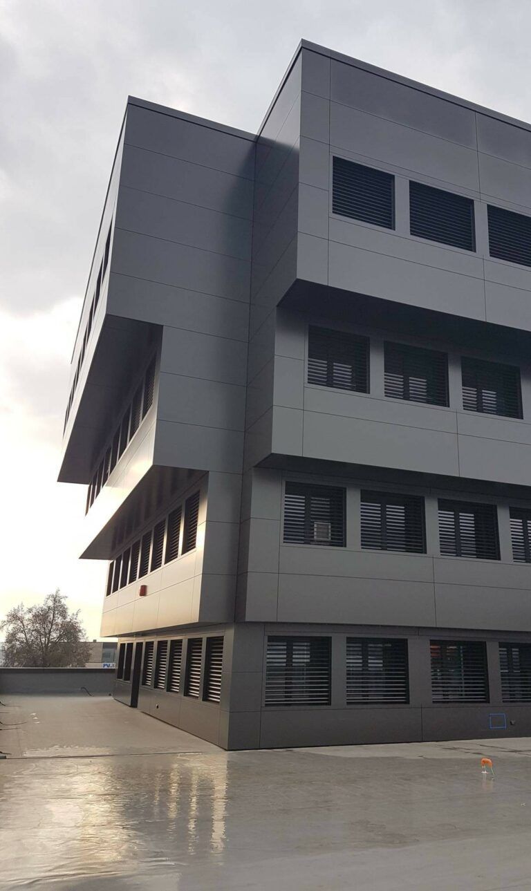 Edificio moderno grigio con file di finestre e sporgenze.