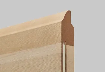 Vista ravvicinata del telaio della porta in legno con parte superiore curva decorativa e superficie strutturata.