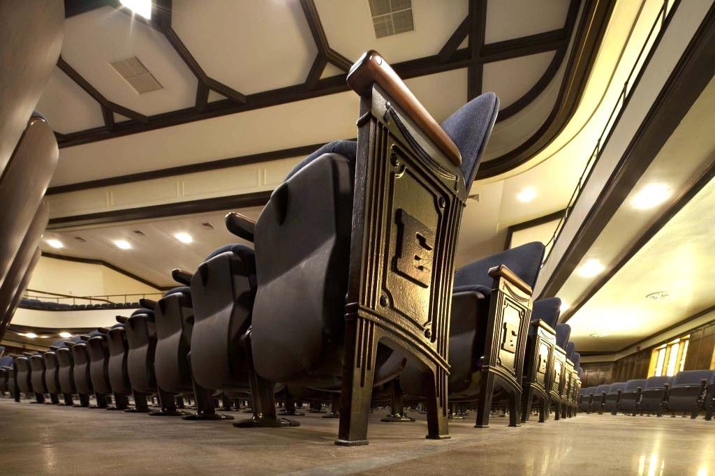 Low-angle view of empty theater seats in a warm-lit auditorium with a patterned ceiling