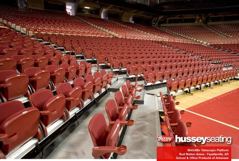 Rows of empty red stadium seats in an indoor arena