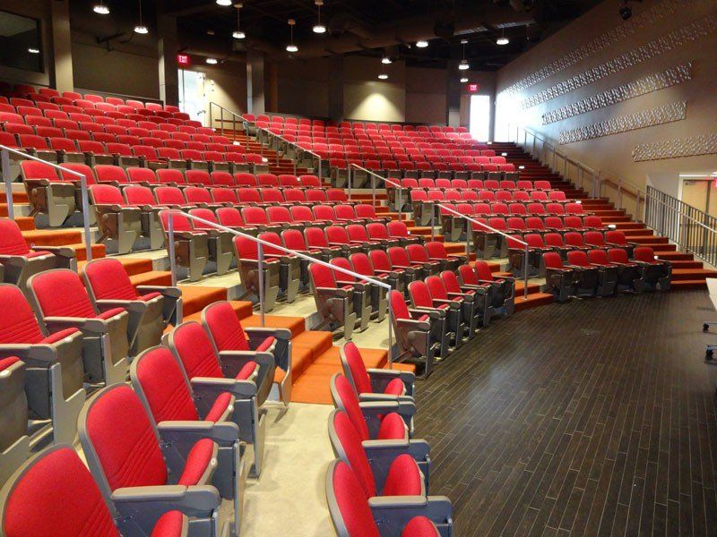 U of A auditorium with rows of red seats and dark wood flooring