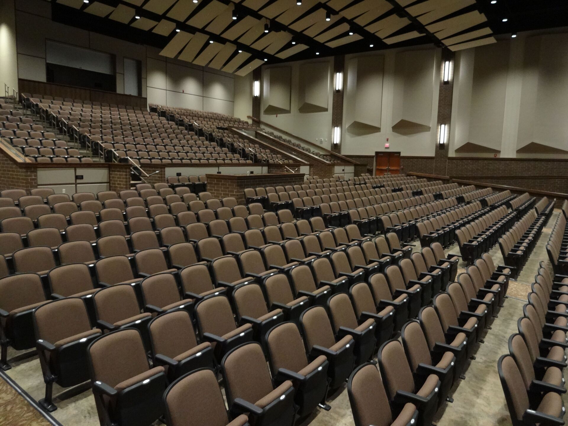 Empty auditorium with rows of brown seats and a high ceiling