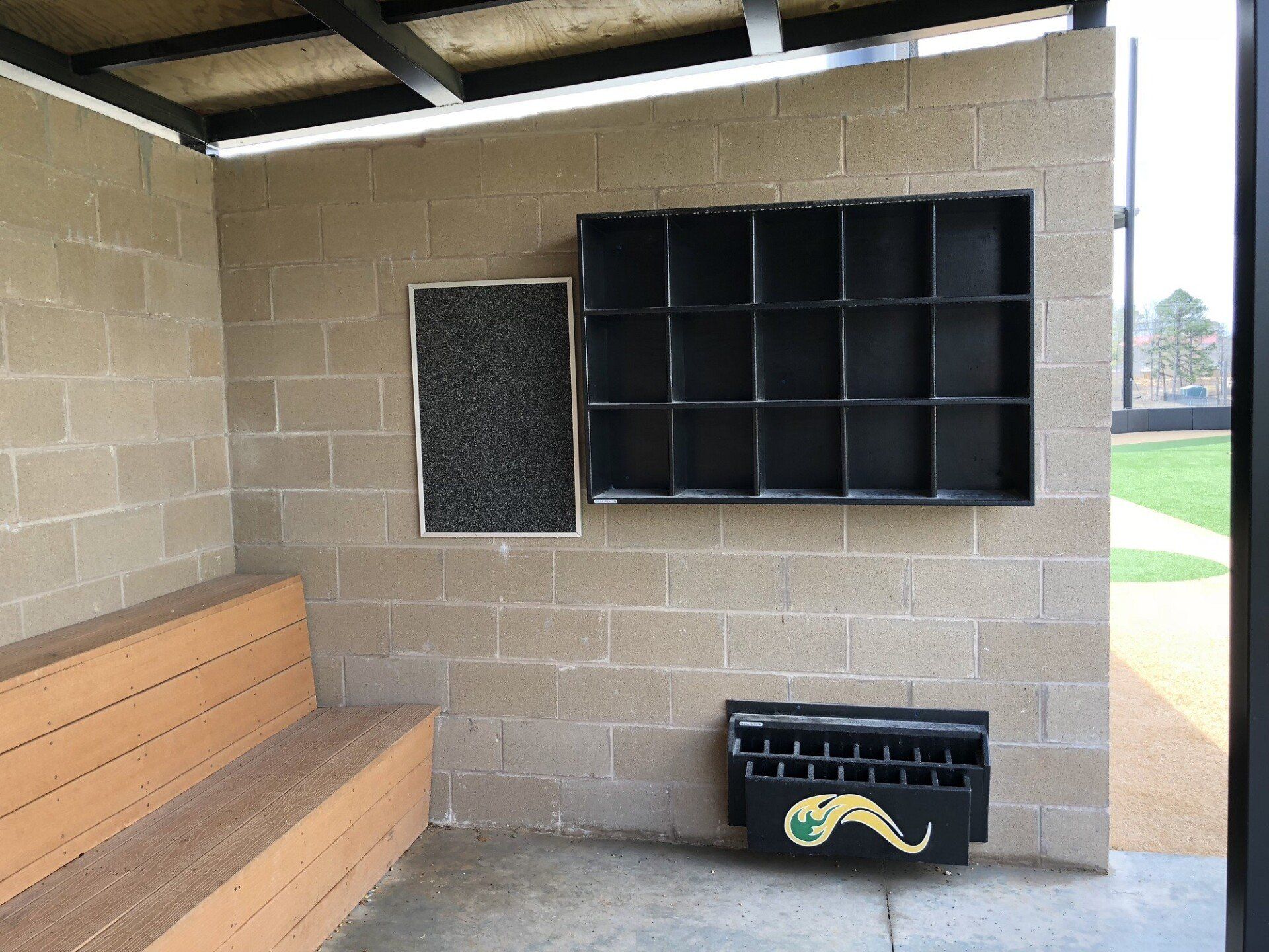 Sheltered park bench beside a brick wall with cubbies and a small mural