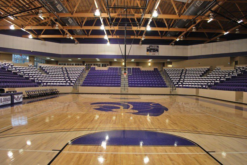 Empty indoor basketball arena with polished court, blue seating, and center-court logo