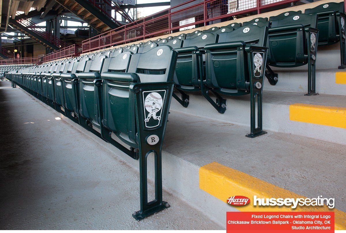 Rows of green stadium seats in an arena with a Hussey Seating logo banner in the corner