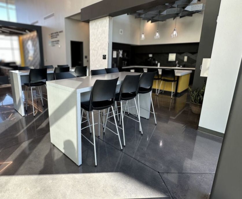 Modern cafe lounge with black chairs, white tables, and a dark bar counter in the background