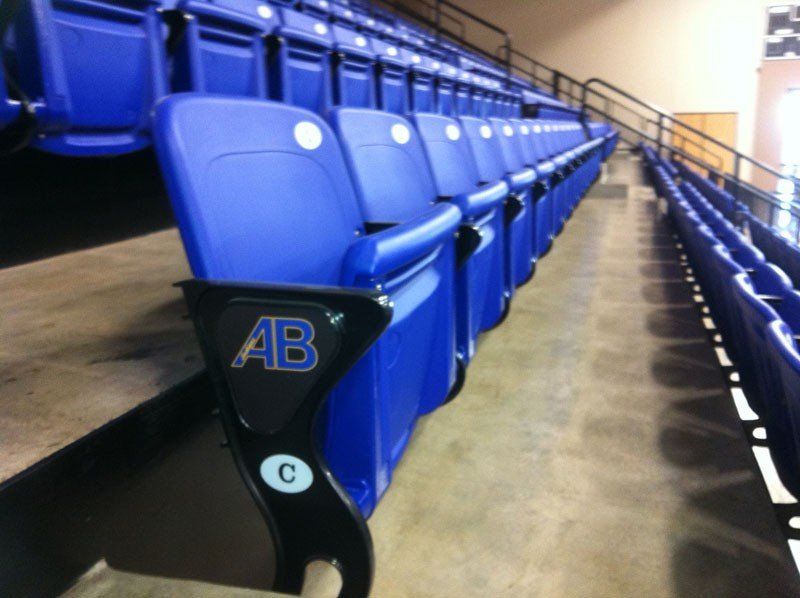 Blue stadium seats in an indoor arena, viewed from the aisle.