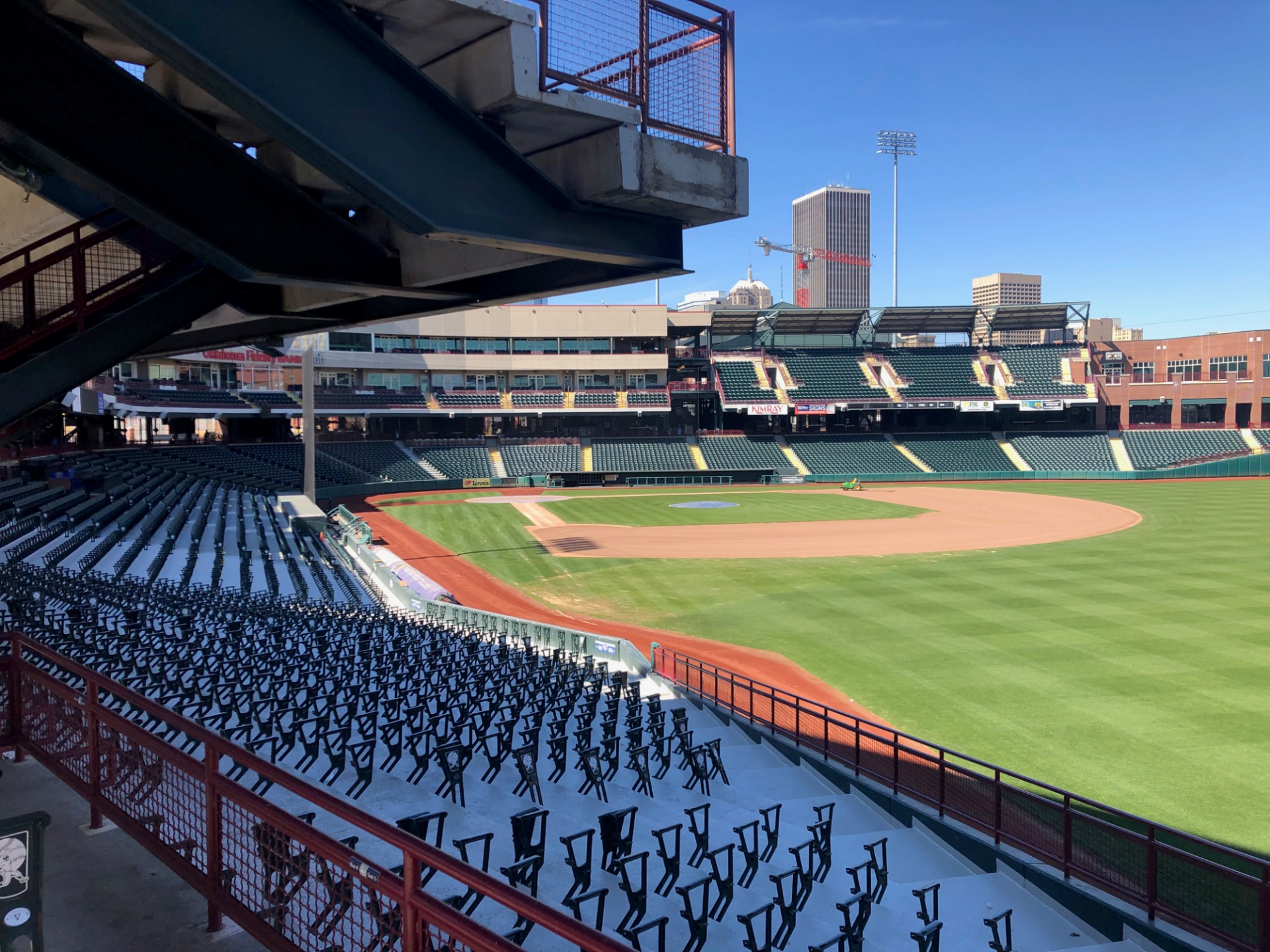 Empty baseball stadium with green field and rows of blue seats under a clear sky