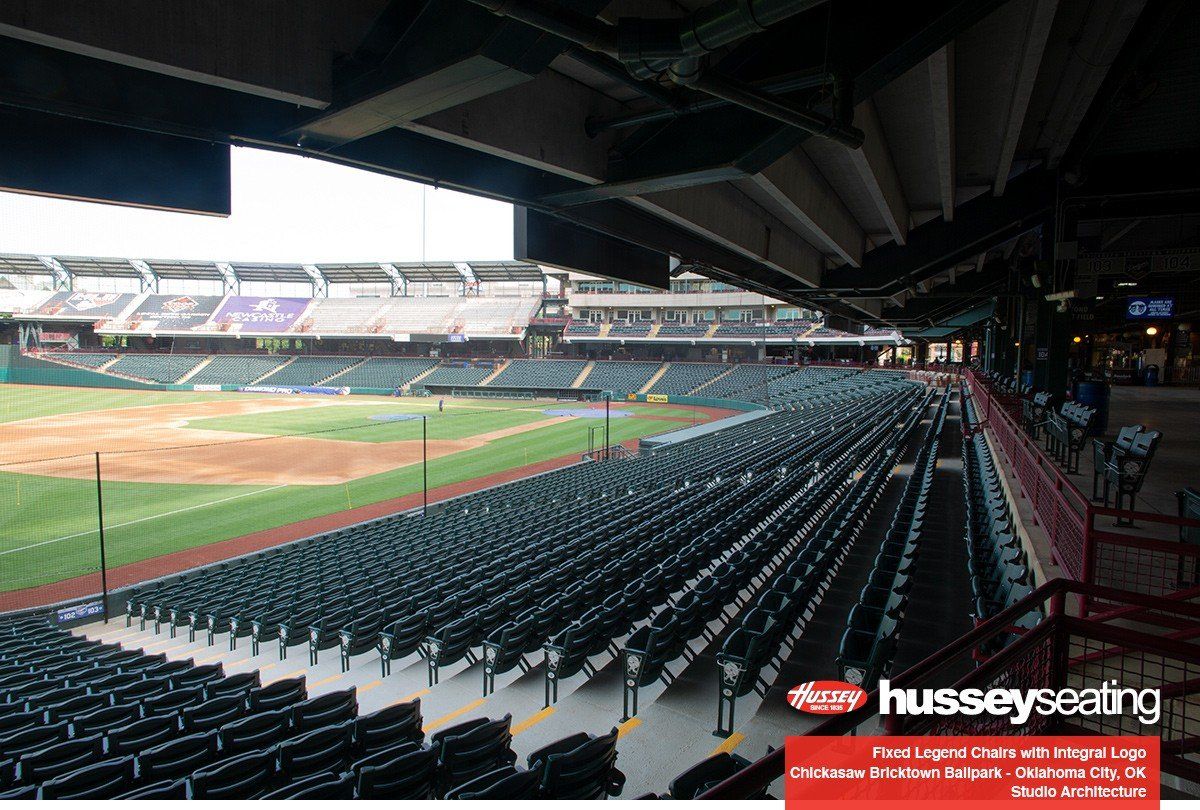 Empty stadium seating overlooking a baseball field under a roof