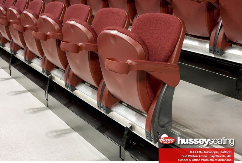 Fold-up red stadium seats in a row on a metal bleacher platform